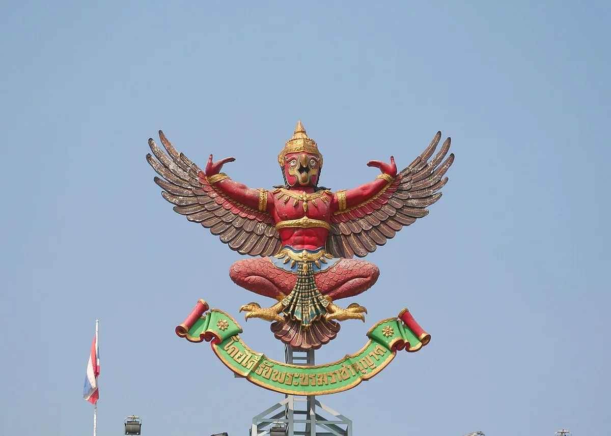 Red and gold Garuda sculpture on a building in Bangkok.